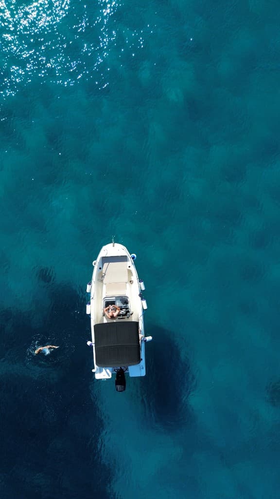 Guest swimming in clear water below a rocky cliff on tour